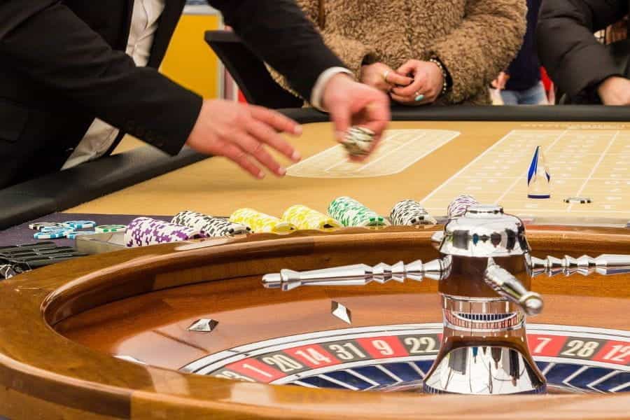 A player lays down chips at a roulette wheel.