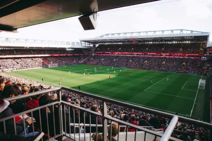 A crowd of spectators watches a football match at a stadium.