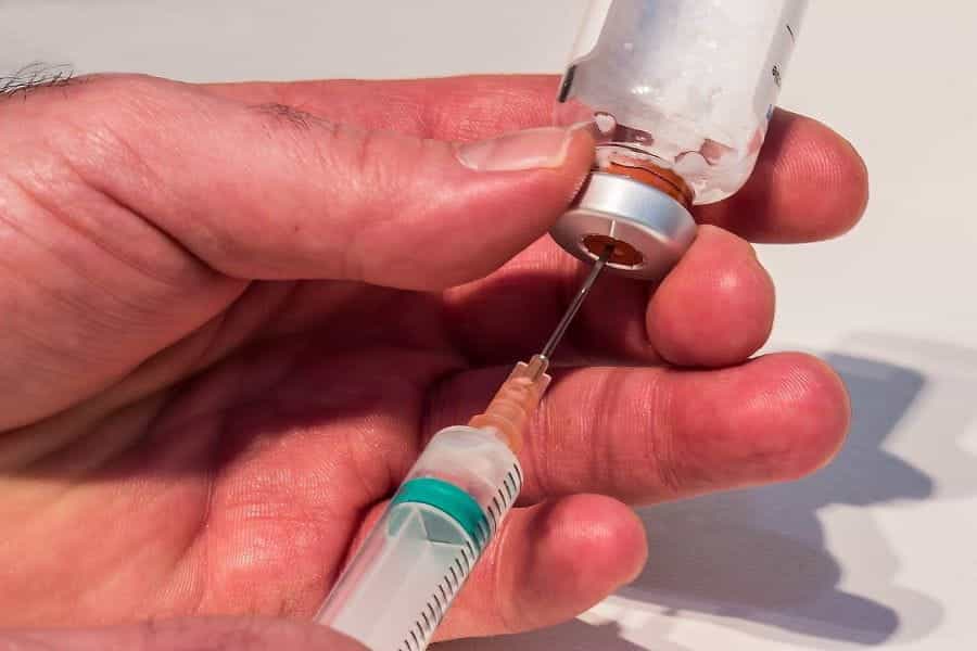 A needle drawing a drug out of a medical vial.