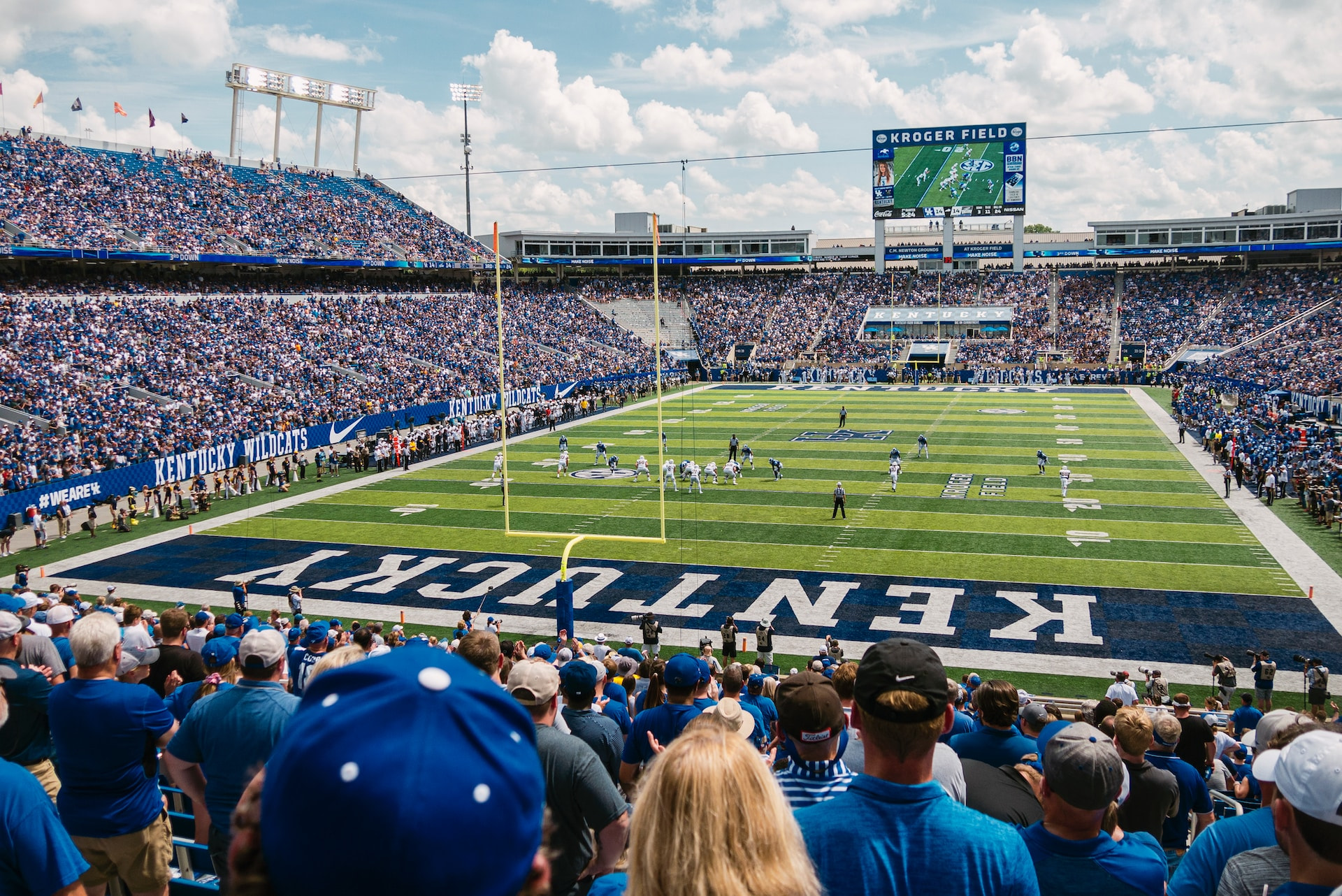 A game of American football being played in a large stadium in Lexington, Kentucky, featuring thousands of spectators watching two teams play against one another on the field.